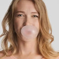 Frau mit blonden Haaren macht eine Kaugummiblase, Nahaufnahme, neutraler Hintergrund