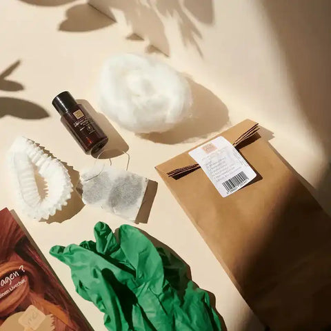 Haarfärbemittel Set mit Flasche, Handschuhen, Watte, Filter, Teebeutel und Tüte auf hellem Untergrund